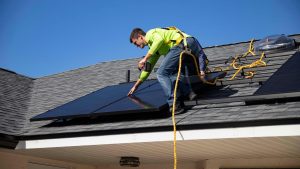 Qualified solar installer in safety gear mounting solar panels on a residential roof in Traralgon